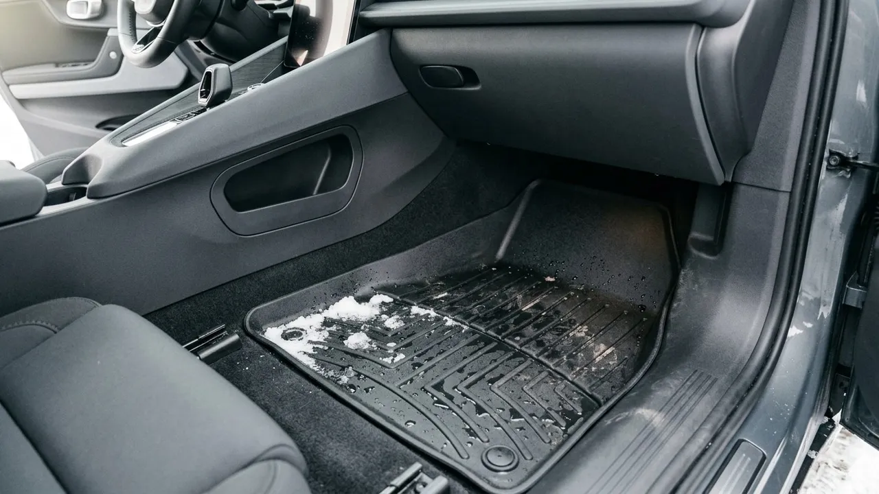 Interior of a modern electric car's front footwell with a black moulded all-weather floor mat with raised edges